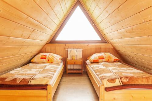 two beds in a wooden cabin with a window at Willa U Góralki in Murzasichle