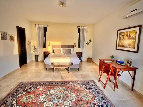a bedroom with a bed and a table and a rug at ג'וליוס סוויטה in Adamit