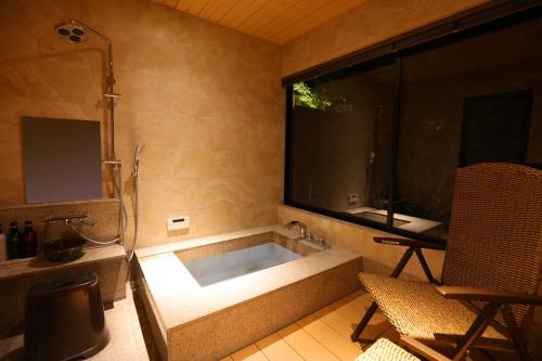 a bathroom with a tub and a large window at yabenomori in Miyanoo