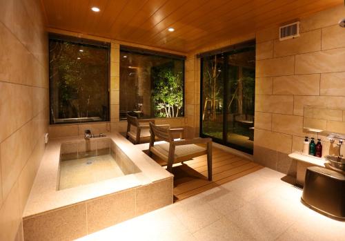 a bathroom with a tub and a table and a chair at yabenomori 