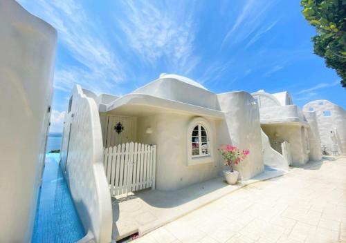 a white house with a swimming pool next to the ocean at Yuki Suite Kourijima in Nakijin