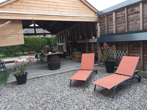 two orange chairs sitting on a gravel patio at Gîte "Au dépôt" in Mesnières-en-Bray