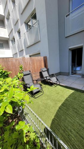 two chairs on a lawn in front of a building at Green Terrace Family Apartment - 2 Terraces, Free Parking, NETFLIX Cinema in Wrocław