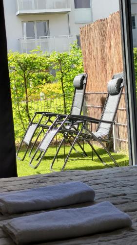 two chairs sitting on the grass outside a window at Green Terrace Family Apartment - 2 Terraces, Free Parking, NETFLIX Cinema in Wrocław