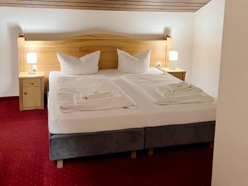 ein Schlafzimmer mit einem großen Bett mit weißer Bettwäsche und Kissen in der Unterkunft Hotel Gundl Alm in Schliersee