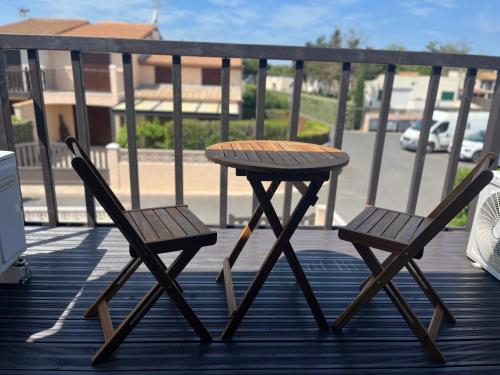 a wooden table and two chairs on a deck at Portiragnes Plage PSD04 in Portiragnes