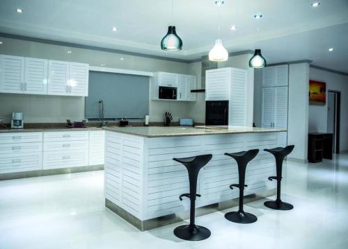 a kitchen with white cabinets and black bar stools at Island Charm of Praslin in Victoria
