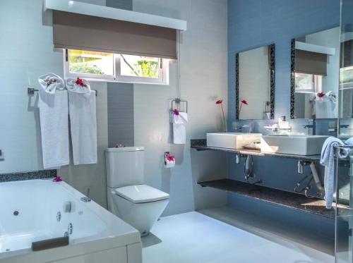 a bathroom with a tub and a toilet and a sink at Island Charm of Praslin in Victoria