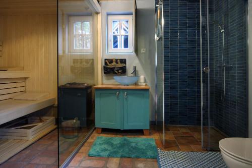 a bathroom with a blue sink and a shower at Pension Kalmus in Smołdziński Las