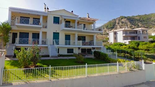 a large white house with a white fence at Derveni Seaside Apartments "Groundfloor" in Derveni