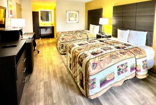 a hotel room with two beds and a desk at Days Inn by Wyndham Charlotte Northlake in Charlotte