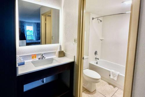 a bathroom with a sink and a toilet and a mirror at Days Inn by Wyndham Charlotte Northlake in Charlotte
