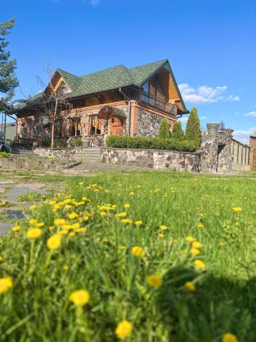 a house with a field of flowers in front of it at Gostynna sadyba Kit Bayun in Teterivka