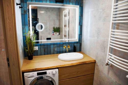 a bathroom with a sink and a washing machine at Luxus Apartment „Goldene Stunde“ in Kołobrzeg