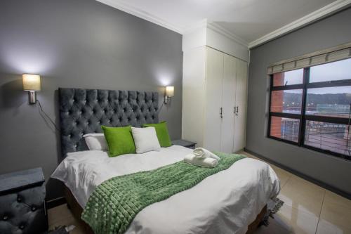 a bedroom with a large bed with green pillows and a window at Stay at The Point - Arabian Affair in Durban