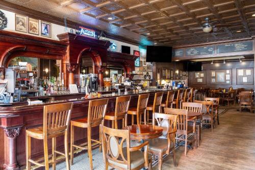a bar in a restaurant with wooden chairs and tables at Gilmore Hotel, Trademark Collection by Wyndham in Ketchikan