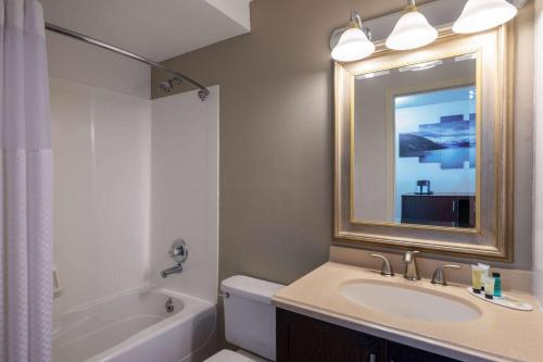 a bathroom with a sink and a tub and a mirror at Ramada by Wyndham Juneau in Juneau