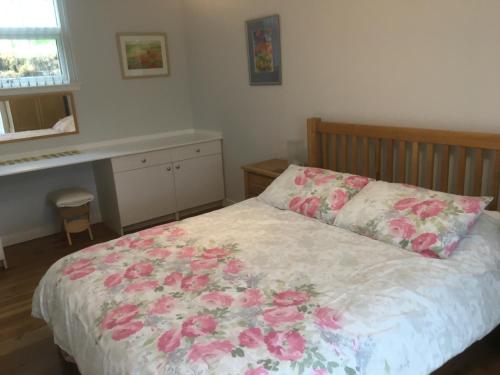 a bedroom with a bed with pink flowers on it at Painter's House in Dunvegan