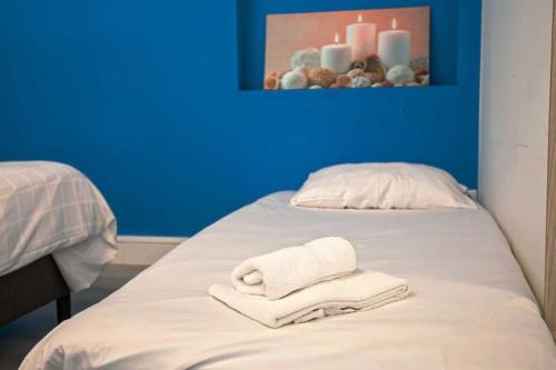 a bed with towels on it with a blue wall at Haarlem Square House City Centre Haarlem in Haarlem