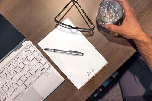 a person holding a glass of water next to a laptop at Hyatt Centric Santa Clara Silicon Valley in Santa Clara