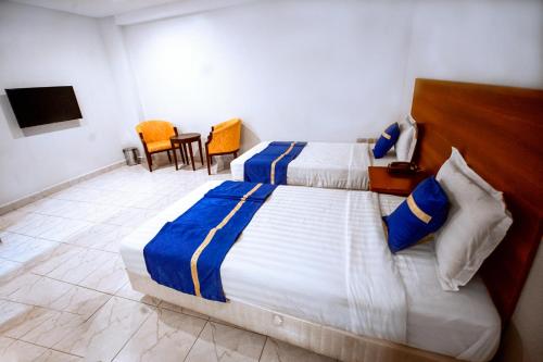 a bedroom with two beds and a table and chairs at Koki Hotel in Kampala