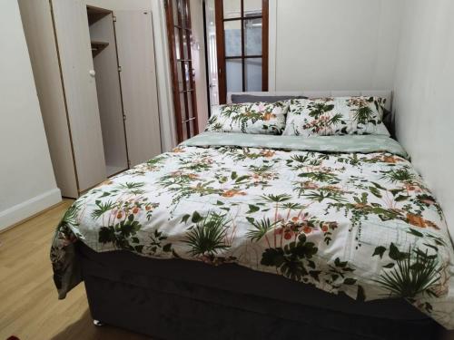 um quarto com uma cama com um edredão floral em Nice Studio Flat in Edmonton, North London em Edmonton