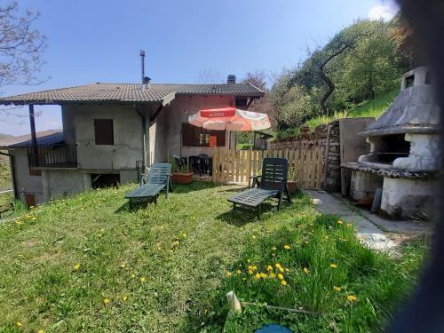 a yard with two chairs and a house with an umbrella at Chalet Niki BELLAGIO in Bellagio