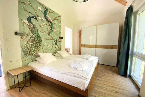 een slaapkamer met een bed met een pauwenschilderij aan de muur bij Appart-Hotel Ernz Noire in Grundhof