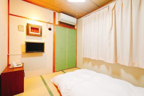 Nara Ryokan - Vacation STAY 49515v في نارا: غرفة نوم بسرير وتلفزيون على جدار