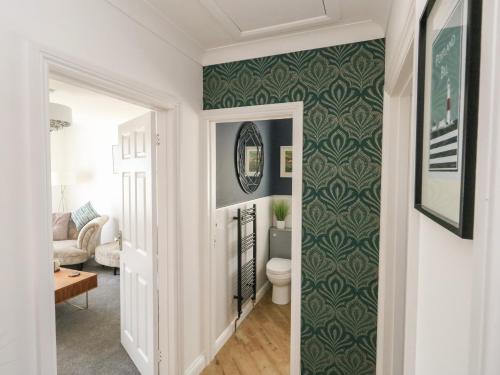 a hallway with a toilet and green wallpaper at The Willows in Weymouth