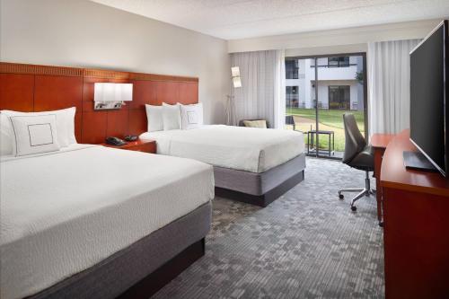 a hotel room with two beds and a desk at Courtyard by Marriott Atlanta Airport South/Sullivan Road in Atlanta