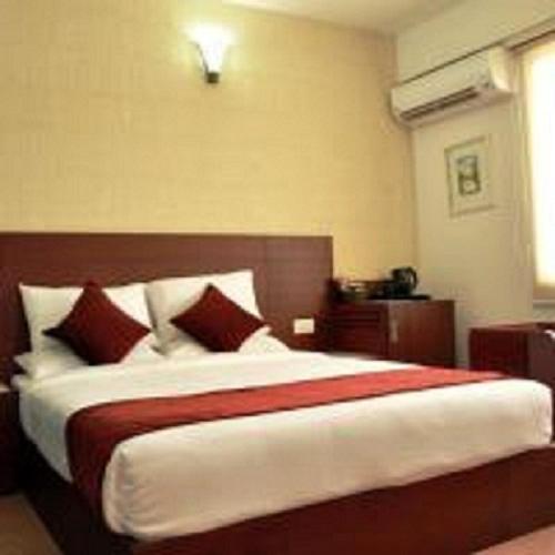 a bedroom with a large bed with red and white pillows at Hotel Olive Eva in Kakkanad