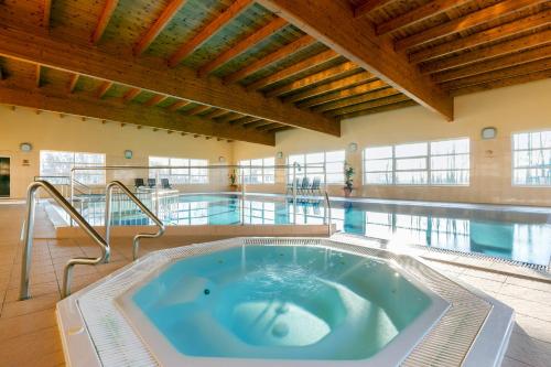 a large pool with a hot tub in a building at Kamienica Parkowa in Dąbki