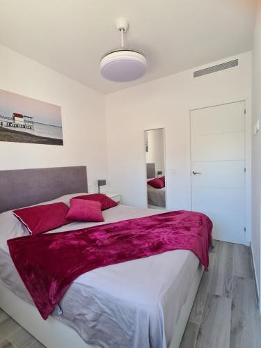 a white bedroom with a large bed with red pillows at Luxe nieuwbouw appartement op 50m van de zee in San Javier