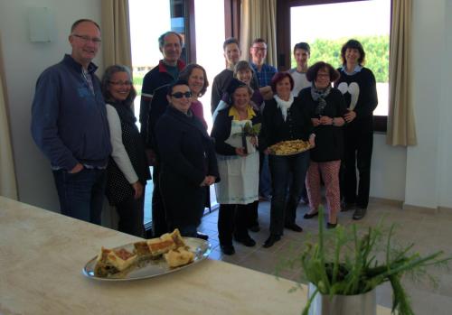 a group of people standing in a room with a plate of food at Hotel La Tartaruga Bianca in Valledoria