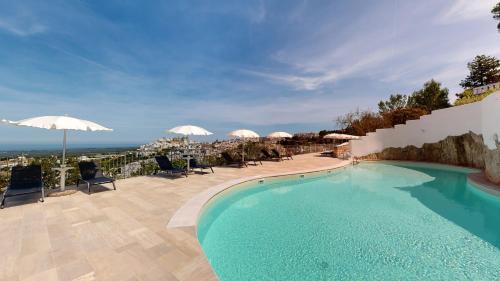 a swimming pool with chairs and umbrellas on a patio at Monte Sarago Villas in Ostuni