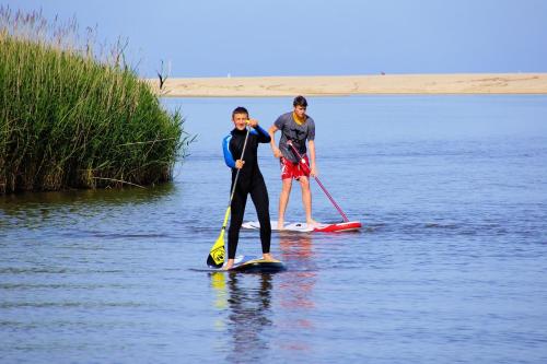 two men are standing on paddle boards in the water at Hotel La Tartaruga Bianca in Valledoria