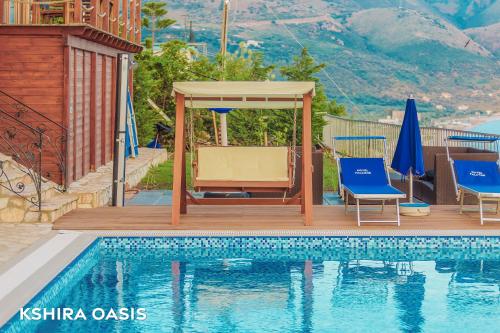 a swimming pool with two chairs and a gazebo next to a house at Kshira Oasis - Luxury 7-Bedroom Vila in Qeparo