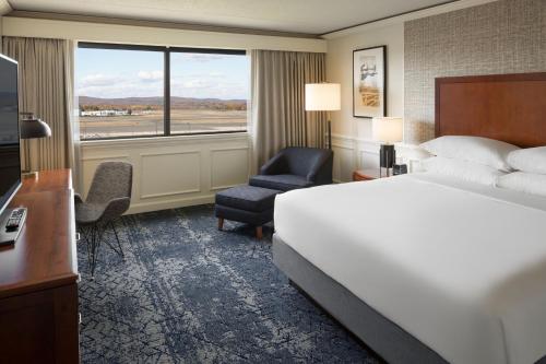 um quarto de hotel com uma cama e uma cadeira e uma janela em Sheraton Hartford Hotel at Bradley Airport em Windsor Locks