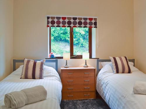 two beds in a room with a window at Oak View Cottage in Llangunllo