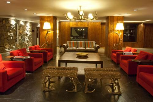 a living room with red couches and a table at Hotel Panamericano Bariloche in San Carlos de Bariloche