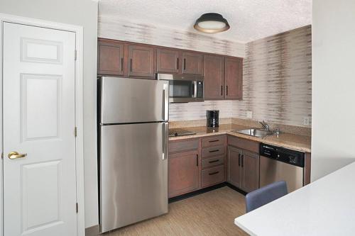 a kitchen with a stainless steel refrigerator and wooden cabinets at Residence Inn Colorado Springs North/Air Force Academy in Colorado Springs