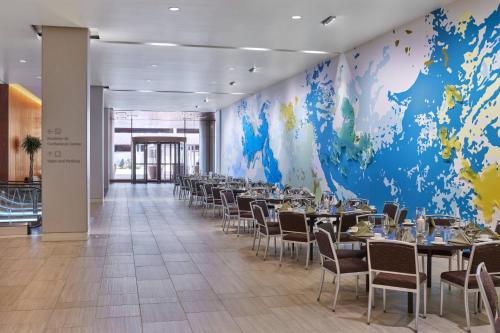 a dining room with tables and chairs and a large mural at The Westin Denver International Airport in Denver