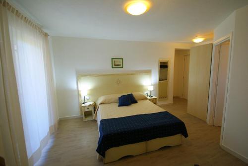 um quarto com uma cama e duas mesas e dois candeeiros em Hotel La Tartaruga Bianca em Valledoria