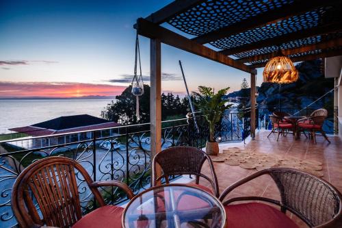 Un balcón con mesas y sillas y vistas al océano. en Casa di Cuore - Beachfront, en Argassi