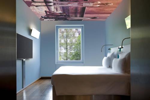 ルツェルンにあるザ ホテル ルツェルン オートグラフ コレクションの青い壁のベッドルーム1室、窓付きのベッド1台が備わります。