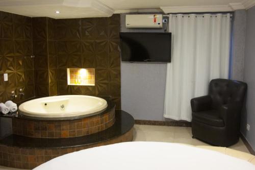 a bathroom with a bath tub and a chair at Lamour Hotel in Taguatinga