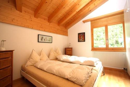 uma cama grande num quarto com tecto em madeira em Residenz Darianne 21 em Leukerbad