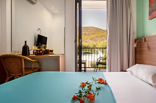 a bedroom with a bed with a blue table with flowers on it at Hotel Pavlou in Poros