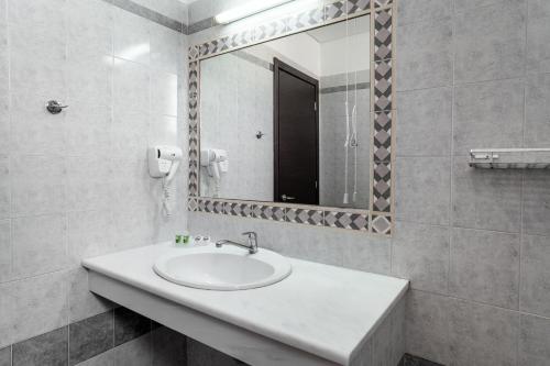 a white bathroom with a sink and a mirror at Hotel Pavlou in Poros